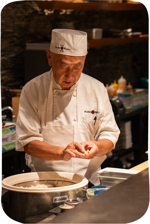 Sushi chef in white uniform preparing food